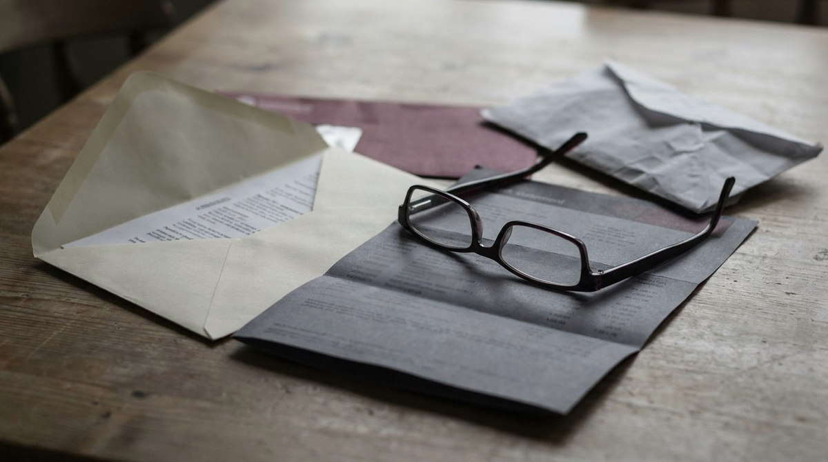 An opened benefit letter, reading glasses and a bank statement on a kitchen table